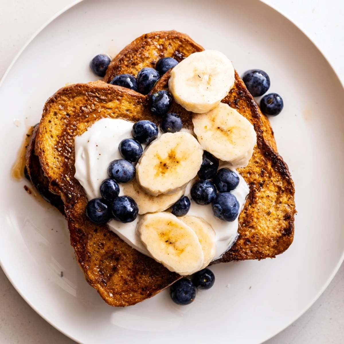 Fluffy Protein French Toast, cooked to perfection, is pictured beside a bowl of fresh fruit and yogurt.