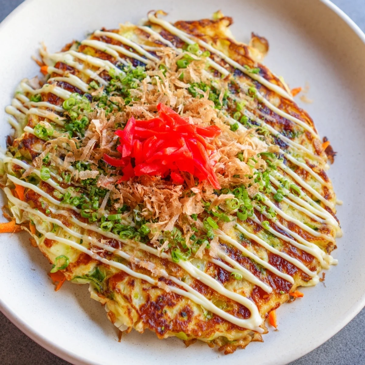 Golden-brown Japanese okonomiyaki pancakes topped with savory sauce, mayo, and dancing bonito flakes are ready to enjoy.