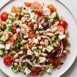 Close-up of Mediterranean White Bean Salad displaying feta, tomatoes and herbs.