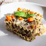 A close-up shot of a delicious vegan lasagna, layered with creamy sauce and vegetables.