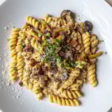 Warm bowl of fusilli with bacon, onions, and mushrooms, a comforting Italian-inspired dinner.