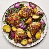 Aromatic steam rises from the sizzling pan-roasted chicken featuring vibrant greens and lemon wedges.