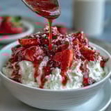 Strawberry compote drizzled over creamy Greek yogurt with a hint of honey and fresh mint garnish.