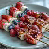 Festive red, white, and blue fruit skewers featuring juicy strawberries, sweet bananas, and fresh blueberries—perfect for summer celebrations.  