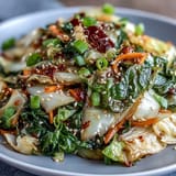 Spicy Cabbage Stir Fry with vibrant vegetables sizzling in a hot wok, topped with sesame seeds.