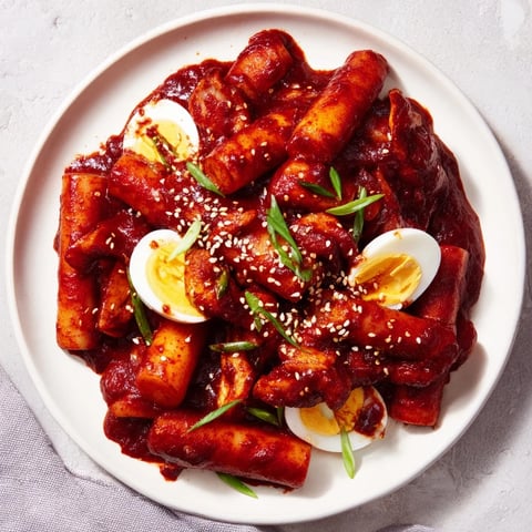 Steaming bowl of Korean tteokbokki: flavorful rice cakes in a vibrant, spicy gochujang sauce.