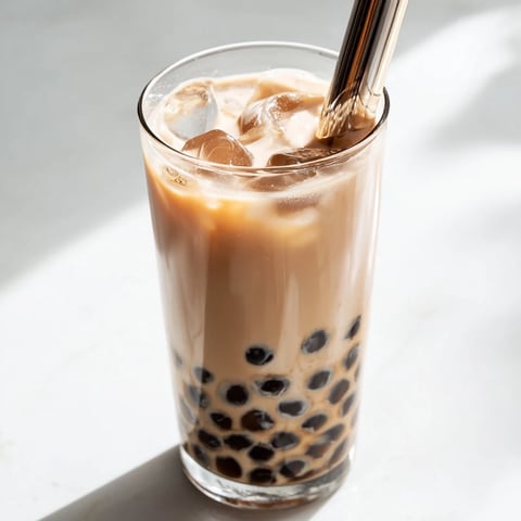 A tall glass of Boba Tea Hack filled with chewy tapioca pearls, creamy milk tea, and ice cubes.