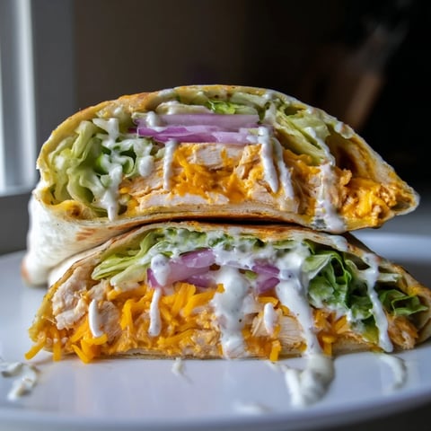 Buffalo Ranch Chicken Wrap sliced in half, showing juicy buffalo chicken, crisp lettuce, and shredded cheddar wrapped in a warm flour tortilla.