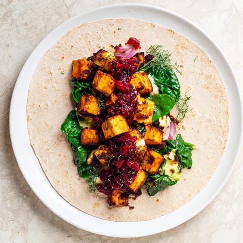 A close-up of a perfectly rolled Roasted Sweet Potato & Black Bean Holiday Wrap, ready to eat with a lime wedge.