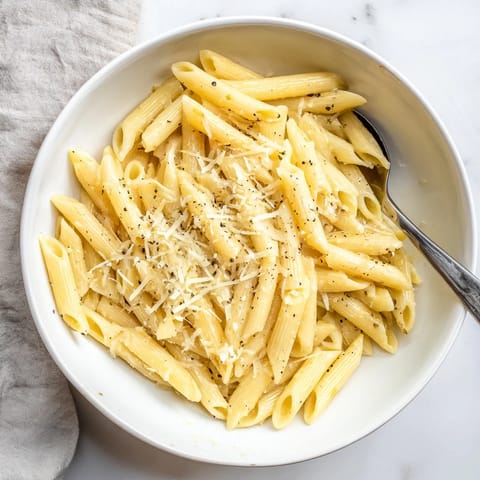 Steaming hot pasta with a touch of olive oil and black pepper, prepared quickly in a microwave-safe bowl for a convenient lunch.  