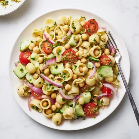 Hearty Lemon Herb Chickpea Pasta Salad served chilled, topped with crumbled feta and kalamata olives, perfect for a light lunch.  