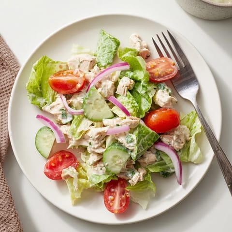 A colorful bowl of Jalapeño Ranch Chicken Salad topped with tortilla strips, cucumber, and red onion slices.  