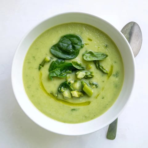 Bright green bowl of creamy Big Green Immunity-Boosting Vegetable Soup with asparagus, spinach, and broccoli garnished with fresh herbs.