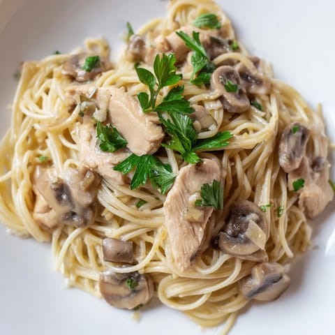 A close-up of Creamy Mushroom Chicken Spaghettini with fresh parsley and grated Parmesan, ready to serve.  