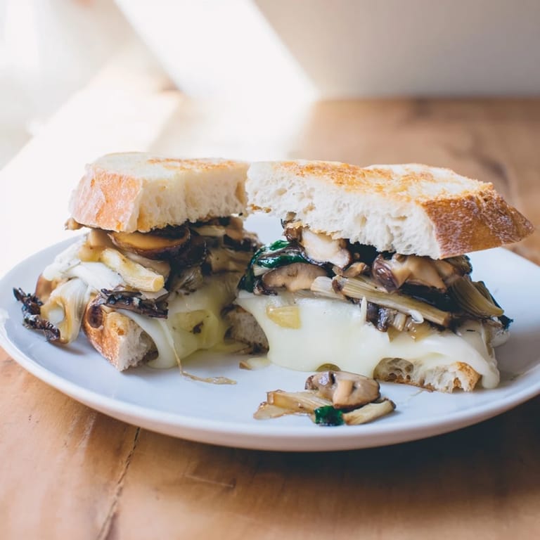 Crispy sourdough cradles melted cheese and savory mushrooms in a Roast Garlic Mushroom & Thyme Grilled Cheese.