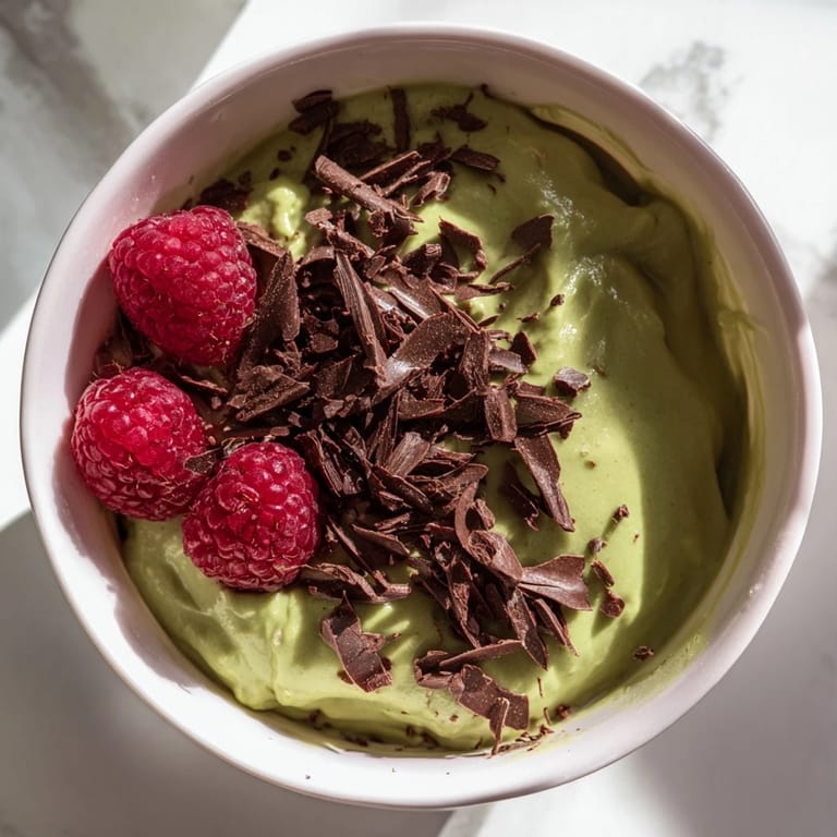 This smooth Avocado Chocolate Pudding shows a swirl of dark chocolate, ready to be devoured with sweet toppings.