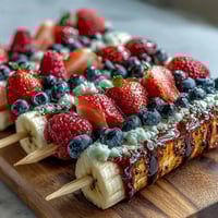Vibrant Fourth of July fruit skewers with strawberries, bananas, and blueberries arranged in patriotic red, white, and blue layers.  